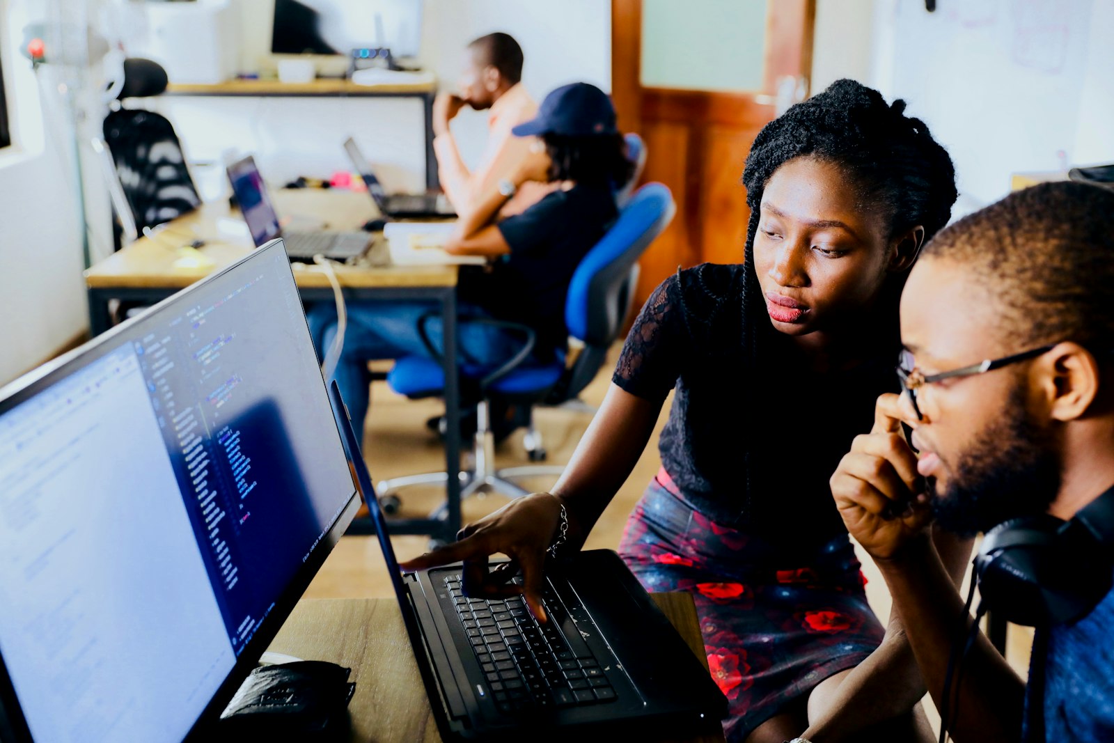 Two colleagues reviewing code together on a monitor in a shared office.
