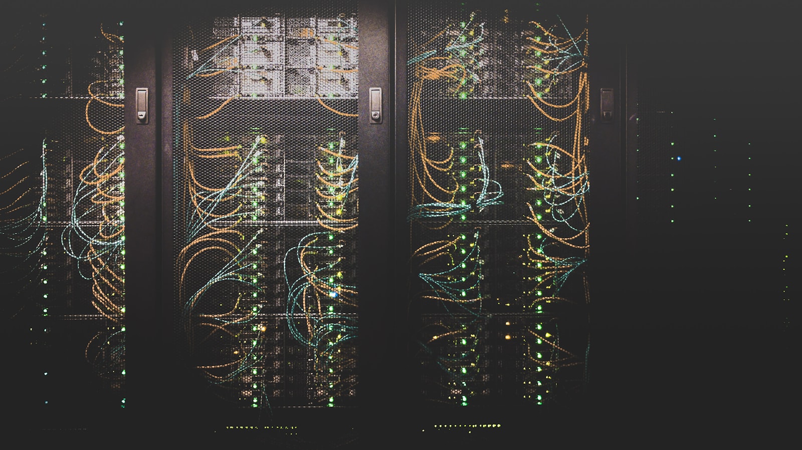 Densely cabled server racks in a data centre, with rows of green status indicators.
