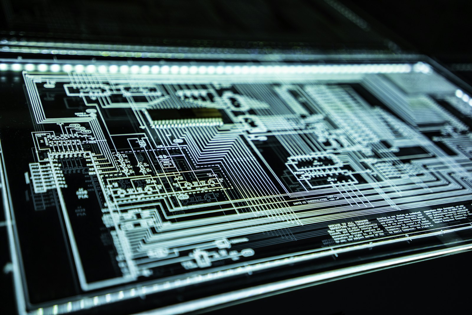 Illuminated circuit board traces glowing on a dark surface.